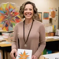 Femme souriante présentant un dessin de rosace dans un atelier d'art-thérapie, illustrant la formation certifiante d'accompagnant par l'expression artistique de la méthode C.A.T®.